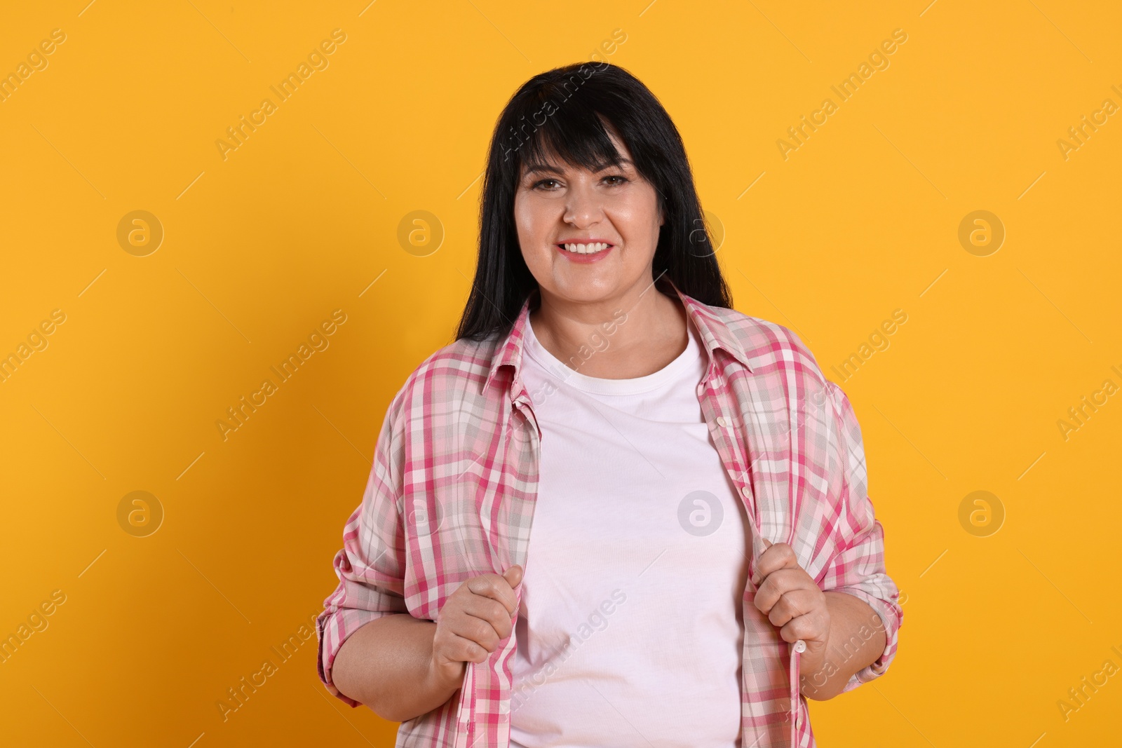 Photo of Beautiful overweight mature woman with charming smile on yellow background