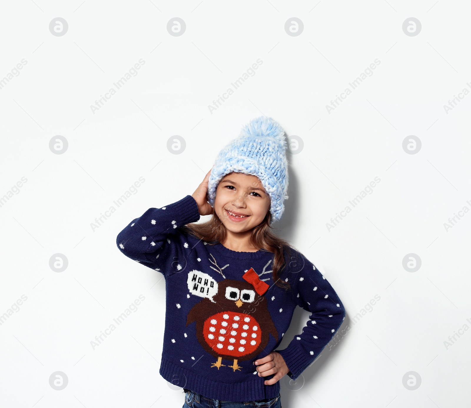 Photo of Cute little girl in Christmas sweater and knitted hat on white background