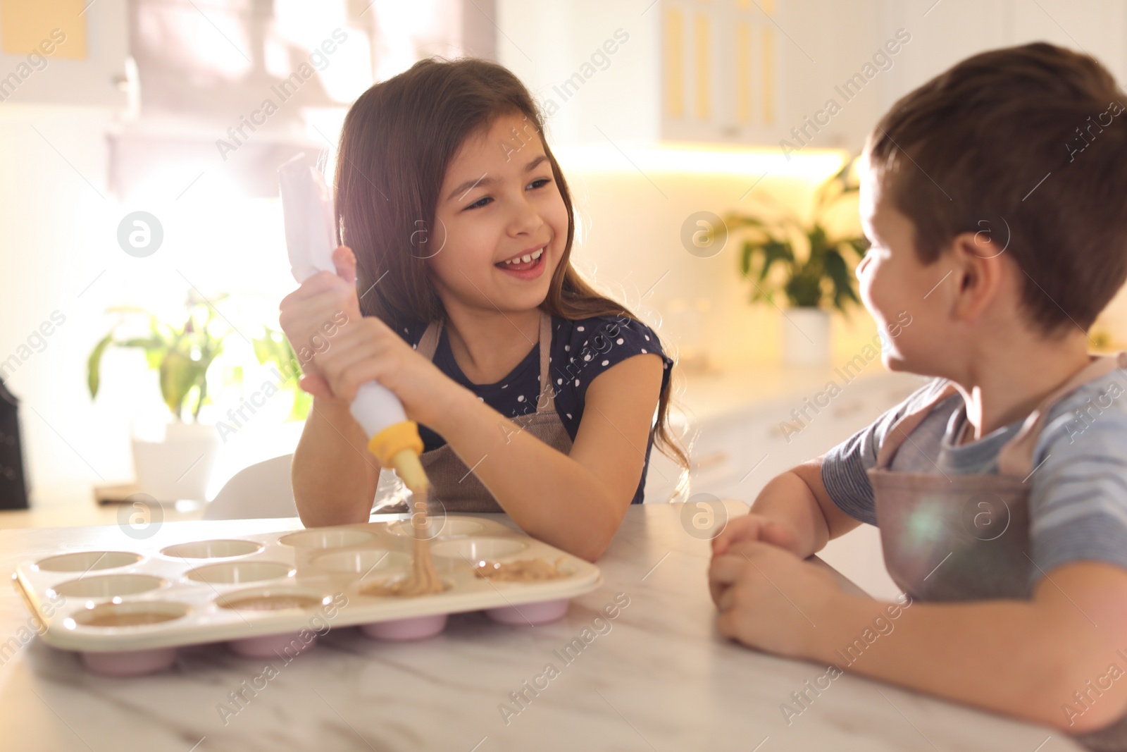 Photo of Cute little children cooking pastry in kitchen at home