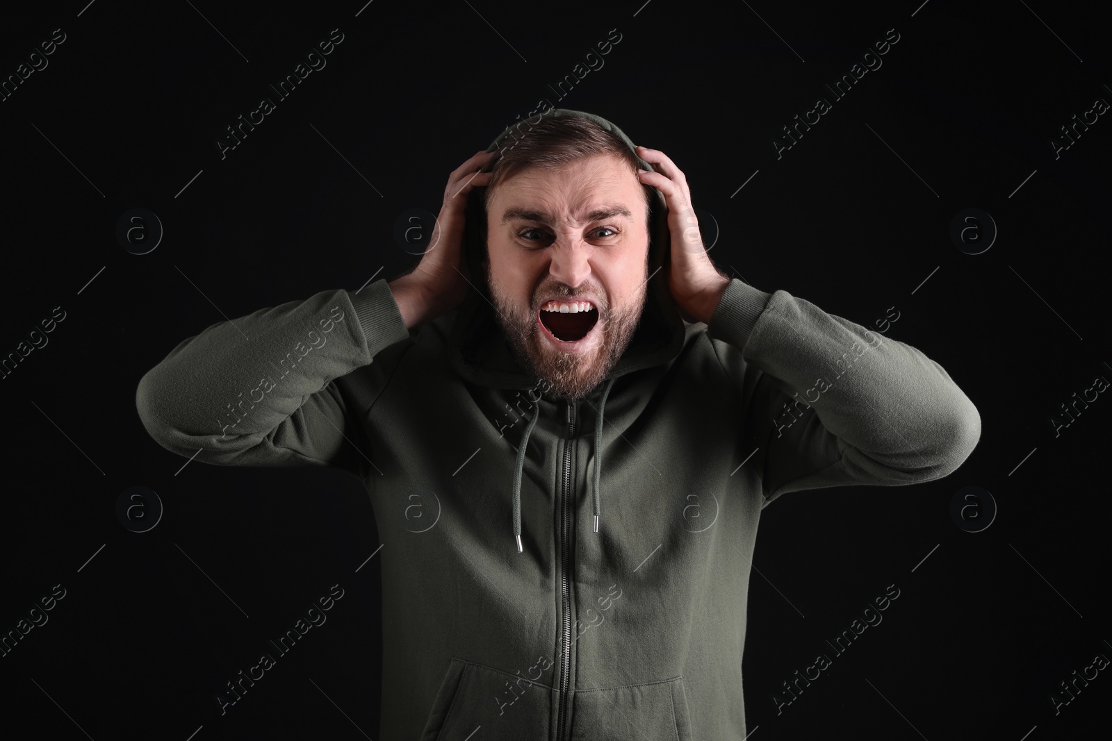 Photo of Portrait of emotional young man on black background. Personality concept