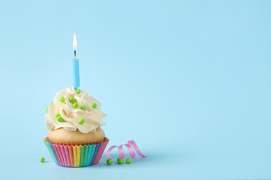 Photo of Birthday cupcake with candle on light blue background. Space for text