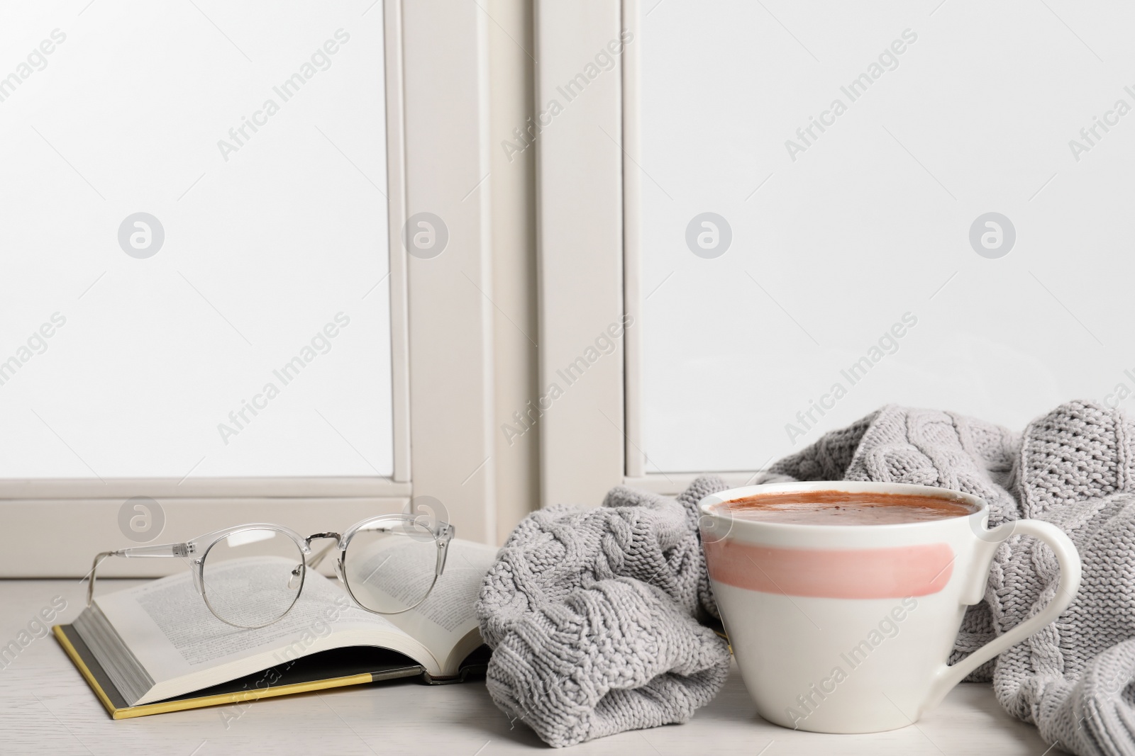 Photo of Composition with cup of hot chocolate and book on windowsill, space for text. Winter drink