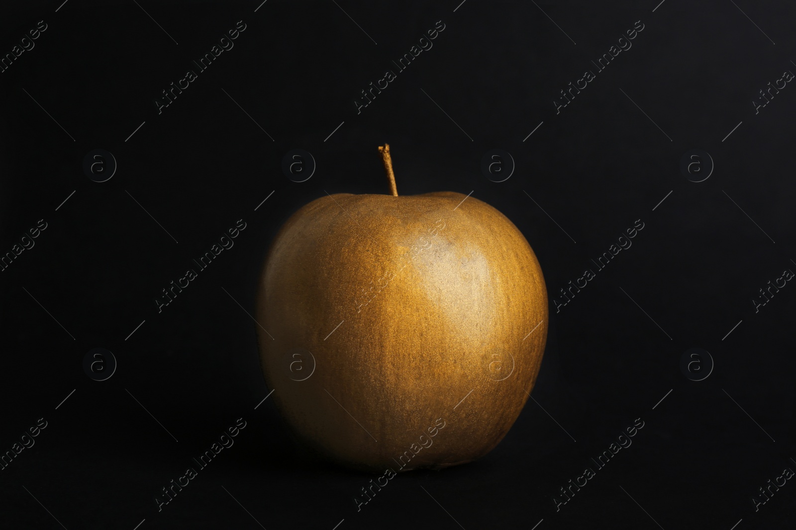 Photo of Gold painted fresh apple on black background