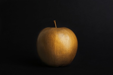 Photo of Gold painted fresh apple on black background