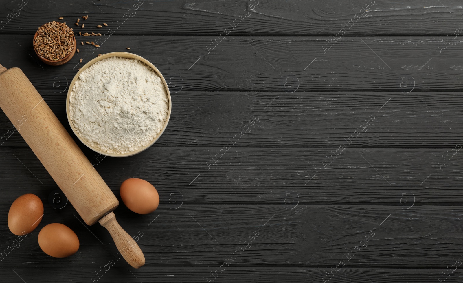 Photo of Flat lay composition with wheat flour and eggs on black wooden table. Space for text