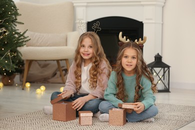 Portrait of cute little girls with Christmas gifts at home