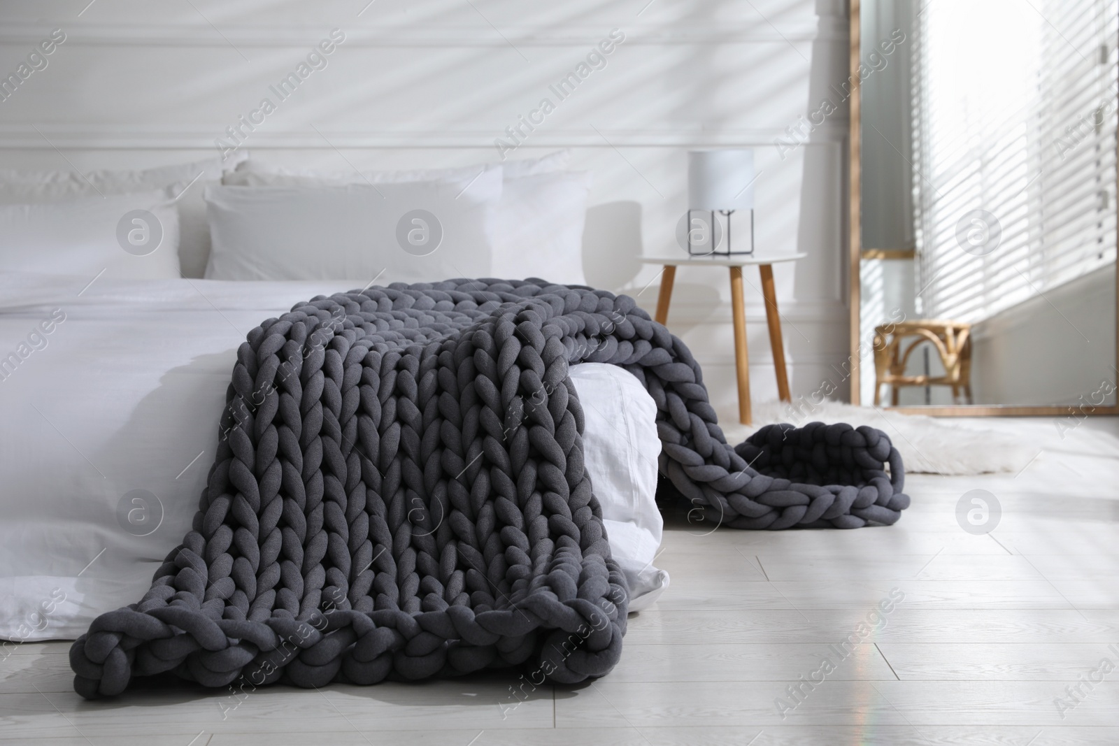 Photo of Soft chunky knit blanket on bed in stylish room interior