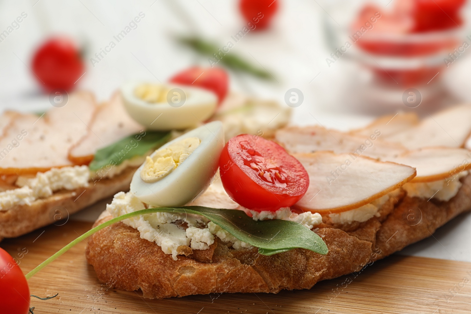 Photo of Board with delicious chicken bruschettas on table, closeup