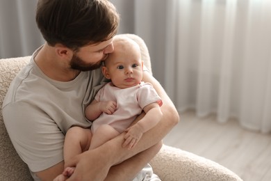 Photo of Father with his cute baby in armchair at home, space for text