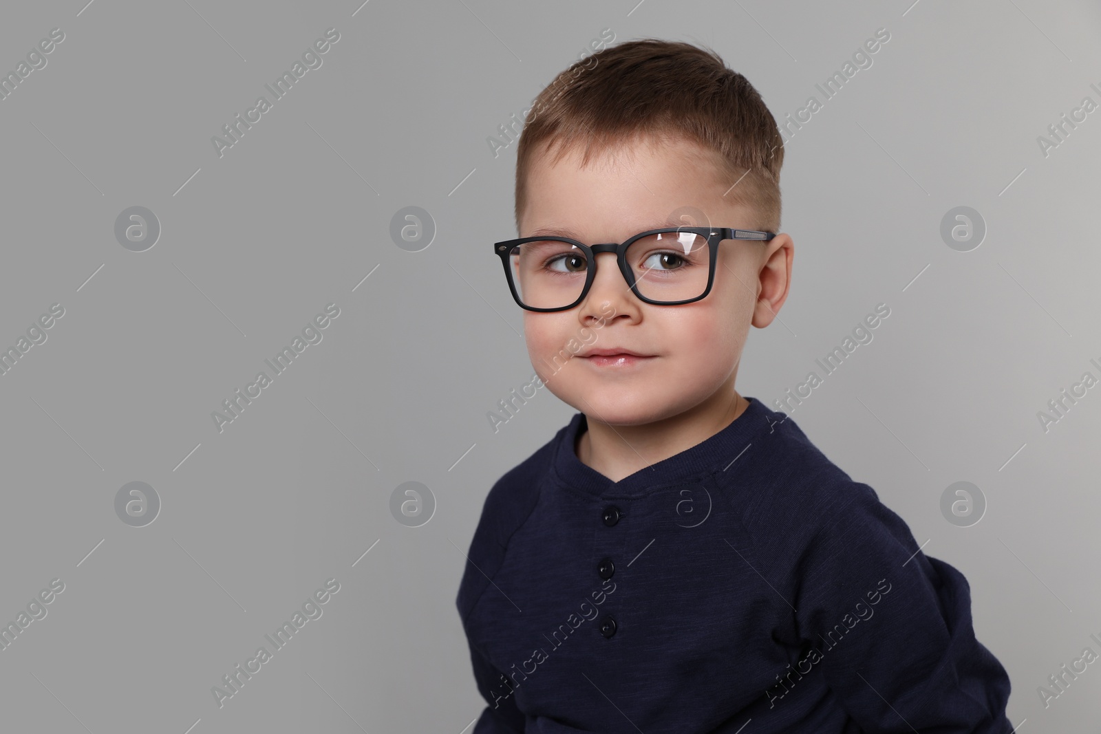 Photo of Cute little boy in glasses on light grey background. Space for text