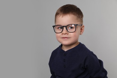 Cute little boy in glasses on light grey background. Space for text