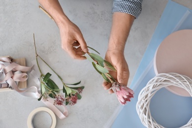 Male florist holding beautiful flower over table, closeup