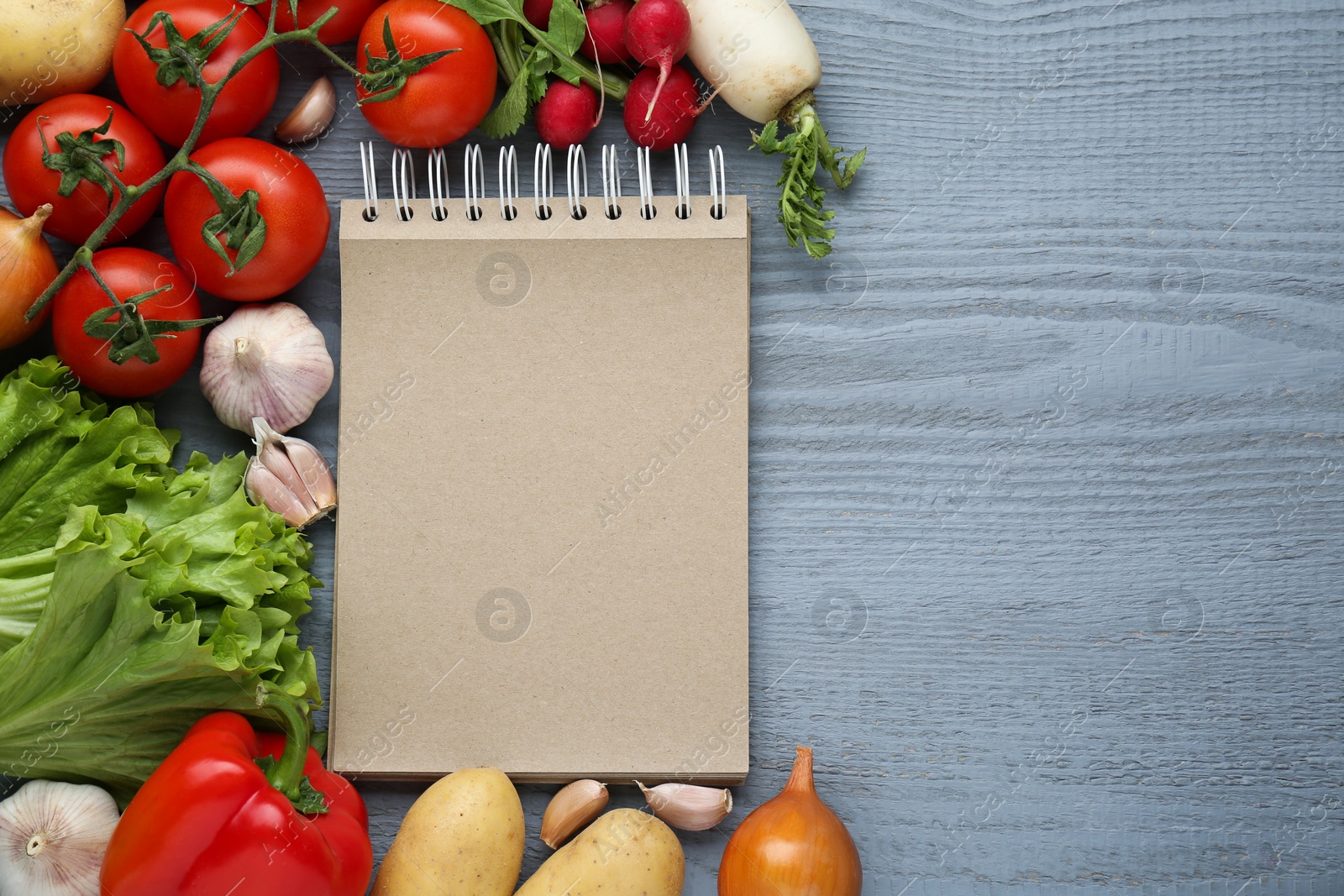 Photo of Blank recipe book and different ingredients on grey wooden table, flat lay. Space for text