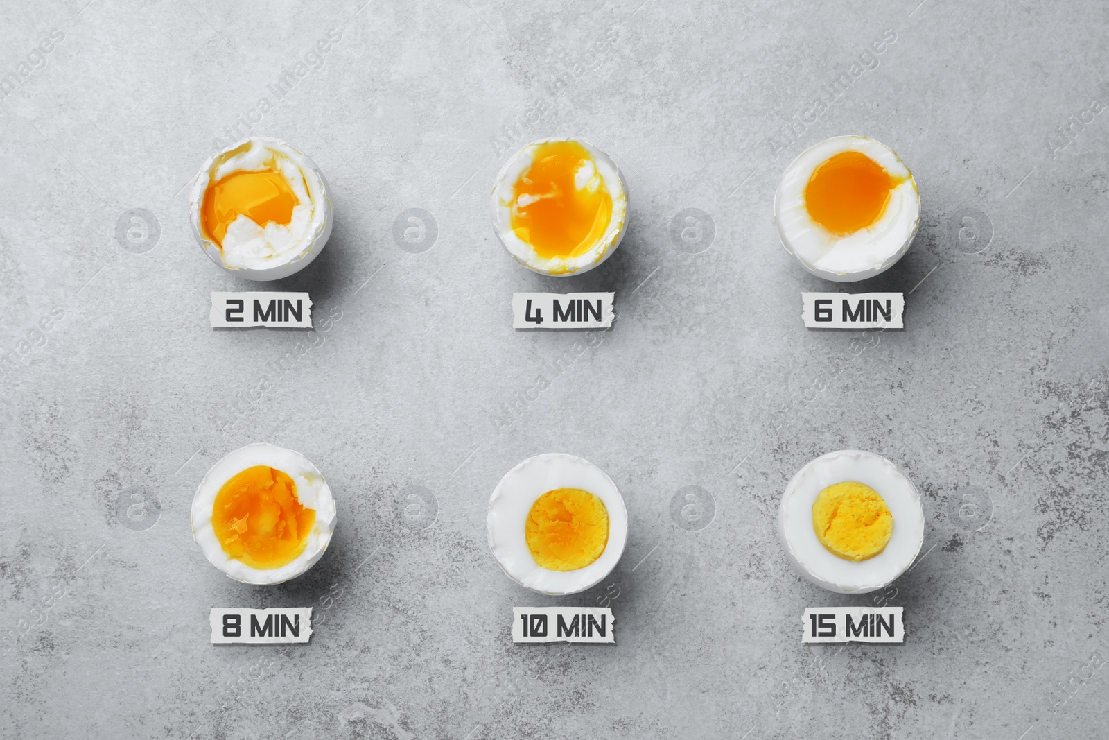 Image of Different readiness stages of boiled chicken eggs on light grey table, flat lay