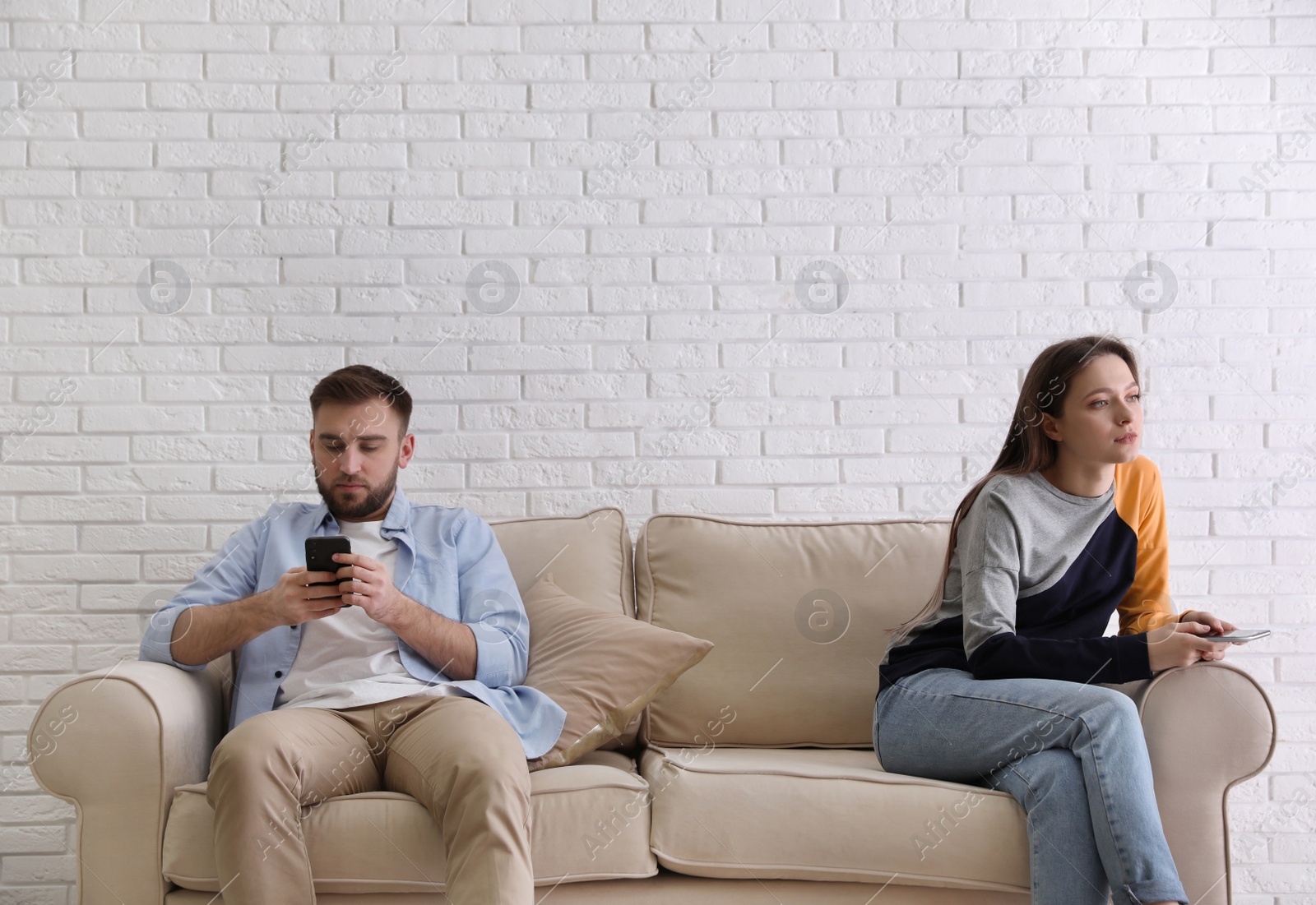 Photo of Couple addicted to smartphones ignoring each other at home. Relationship problems