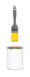 Image of Brush with yellow paint in air over can on white background