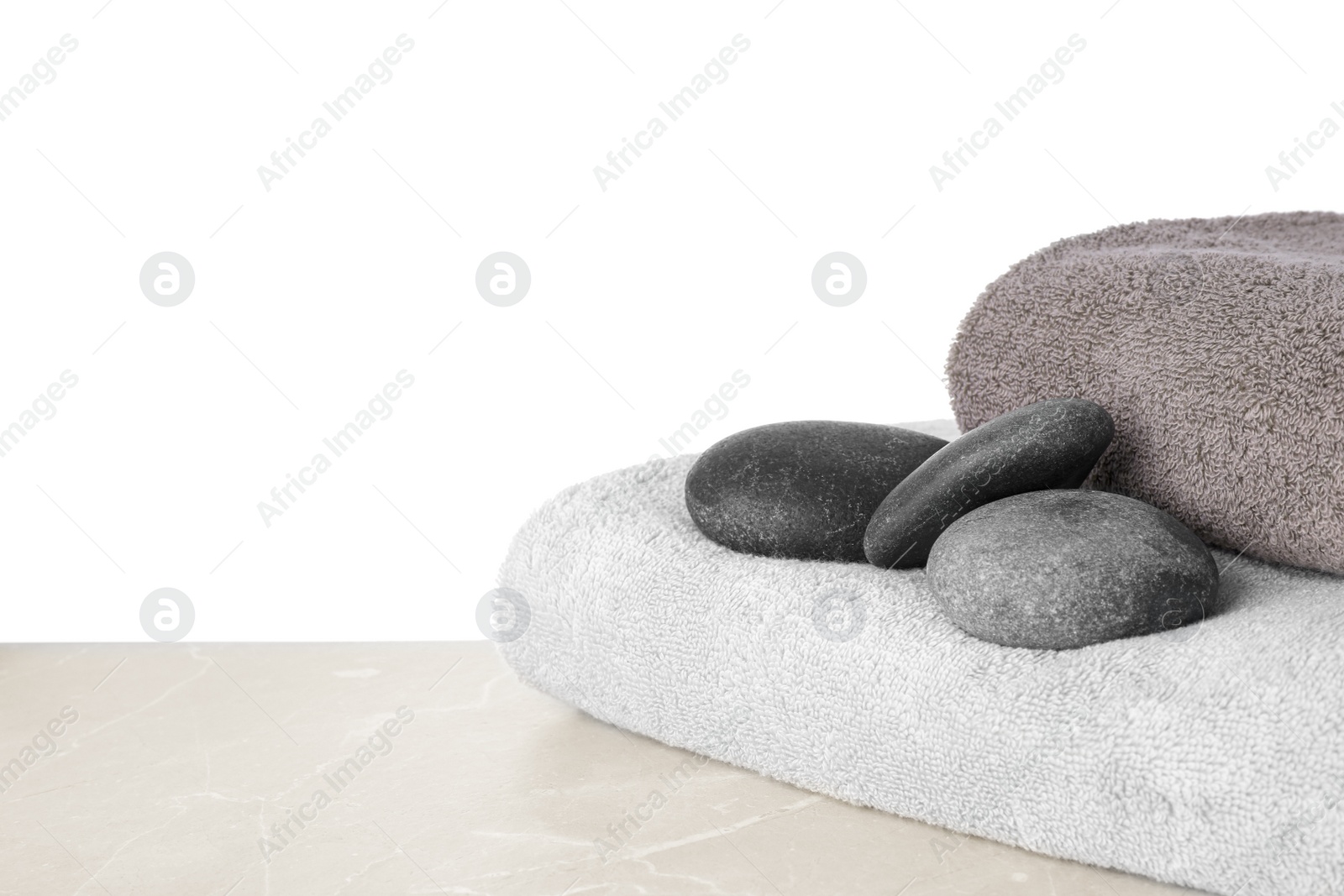 Photo of Towels and spa stones on table against white background