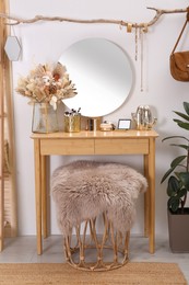 Modern wooden dressing table with mirror near white wall in room