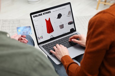Photo of Couple with credit card using laptop for shopping online indoors, closeup