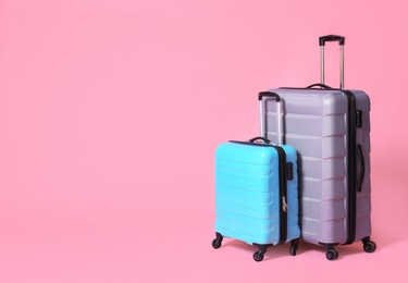 Photo of Modern suitcases on light pink background. Space for text