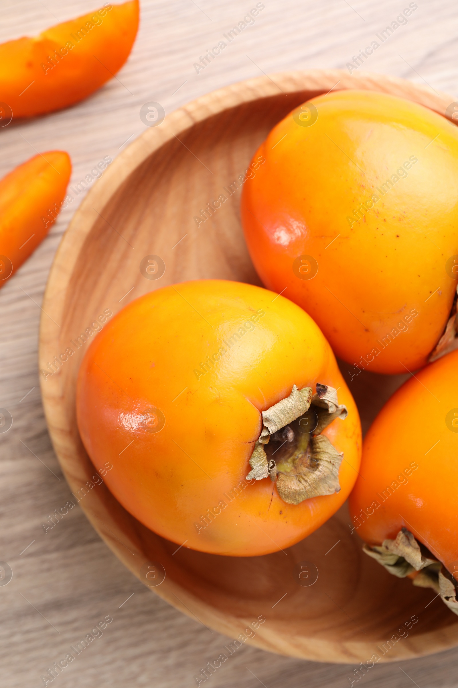 Photo of Delicious ripe persimmons on light wooden table, top view