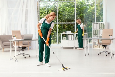 Photo of Team of janitors in uniform cleaning office