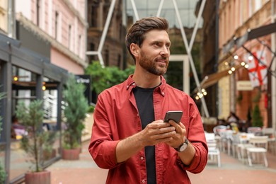 Photo of Handsome man using smartphone on city street