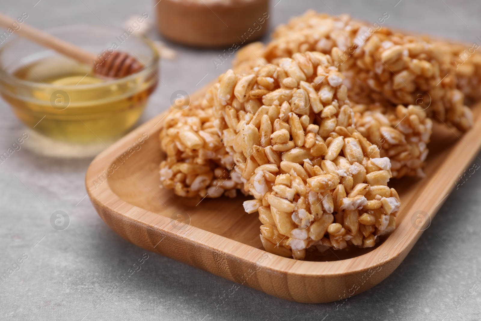 Photo of Plate with puffed rice pieces (kozinaki) on grey table, closeup