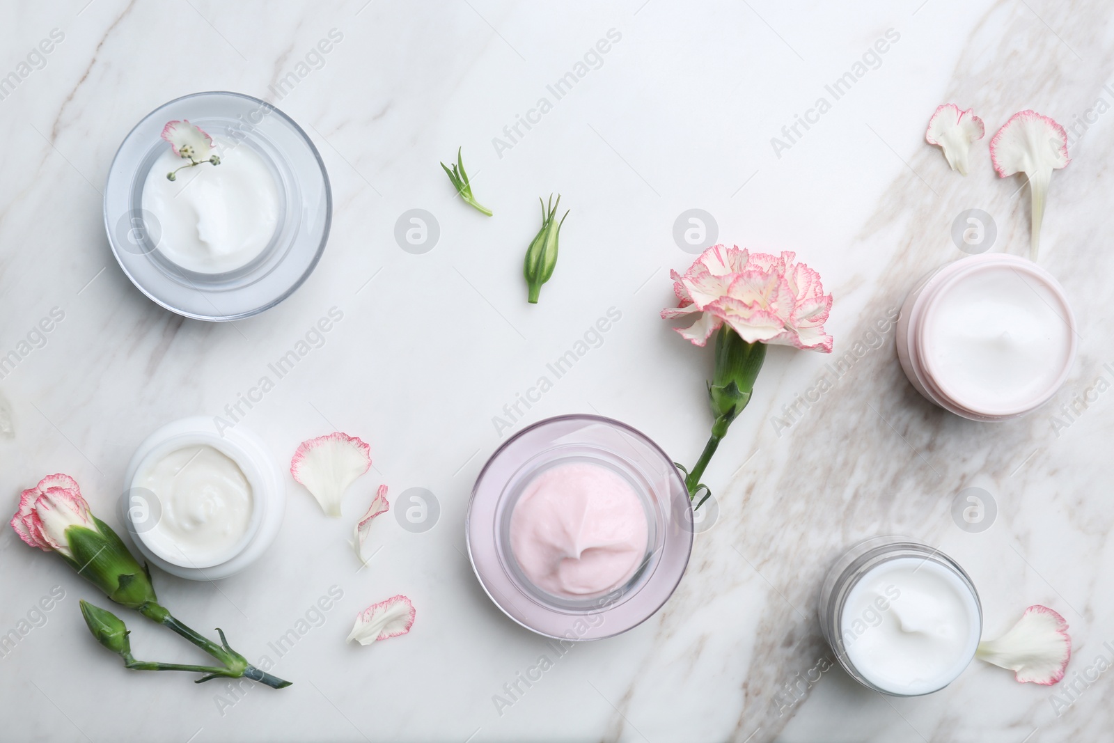 Photo of Jars with different body cream on marble background