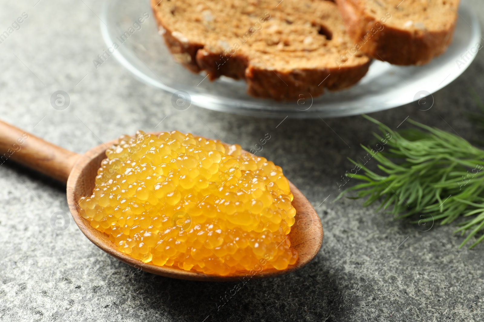 Photo of Fresh pike caviar in spoon, dill and bread on grey table, closeup