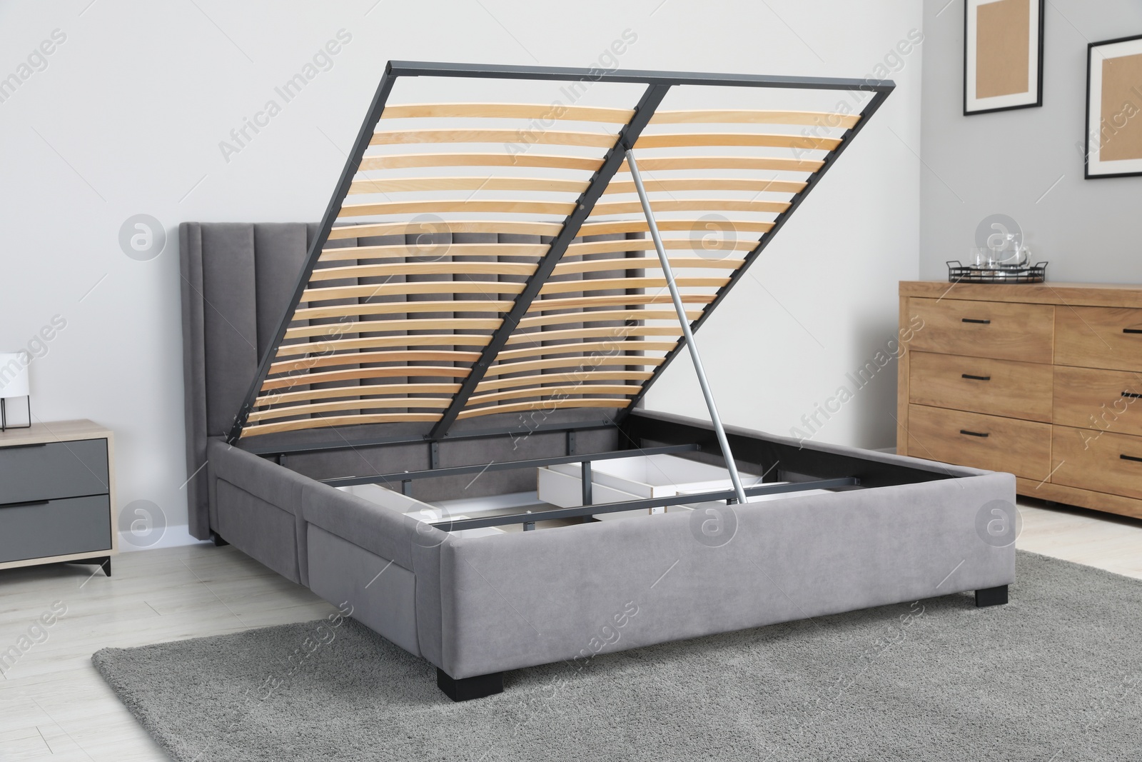 Photo of Comfortable bed with storage space for bedding under lifted slatted base in stylish room