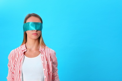 Photo of Young woman wearing blindfold on blue background. Space for text