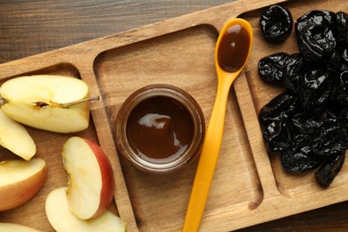 Photo of Tasty baby food in jar, cut apple and dried prunes on wooden table, top view