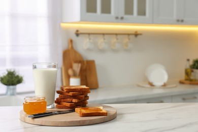 Photo of Breakfast served in kitchen. Crunchy toasts, honey and milk on white marble table. Space for text
