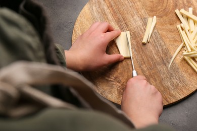 Photo of Woman cutting delicious fresh ripe parsnip at black table, above view