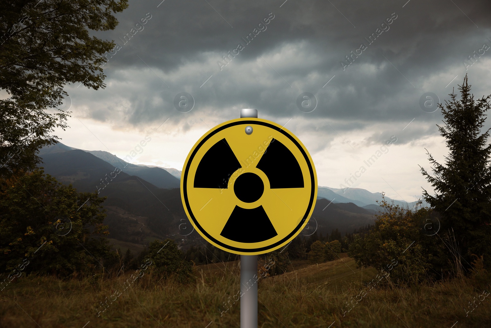 Image of Radioactive pollution. Yellow warning sign with hazard symbol in mountains