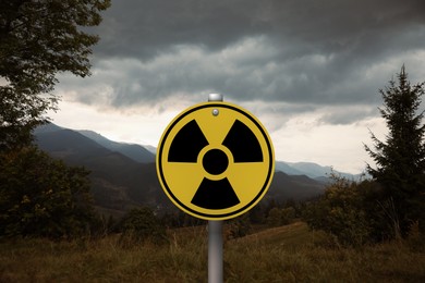 Radioactive pollution. Yellow warning sign with hazard symbol in mountains