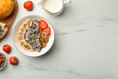 Photo of Bowl of granola with pitahaya, banana and strawberry on white marble table, flat lay. Space for text
