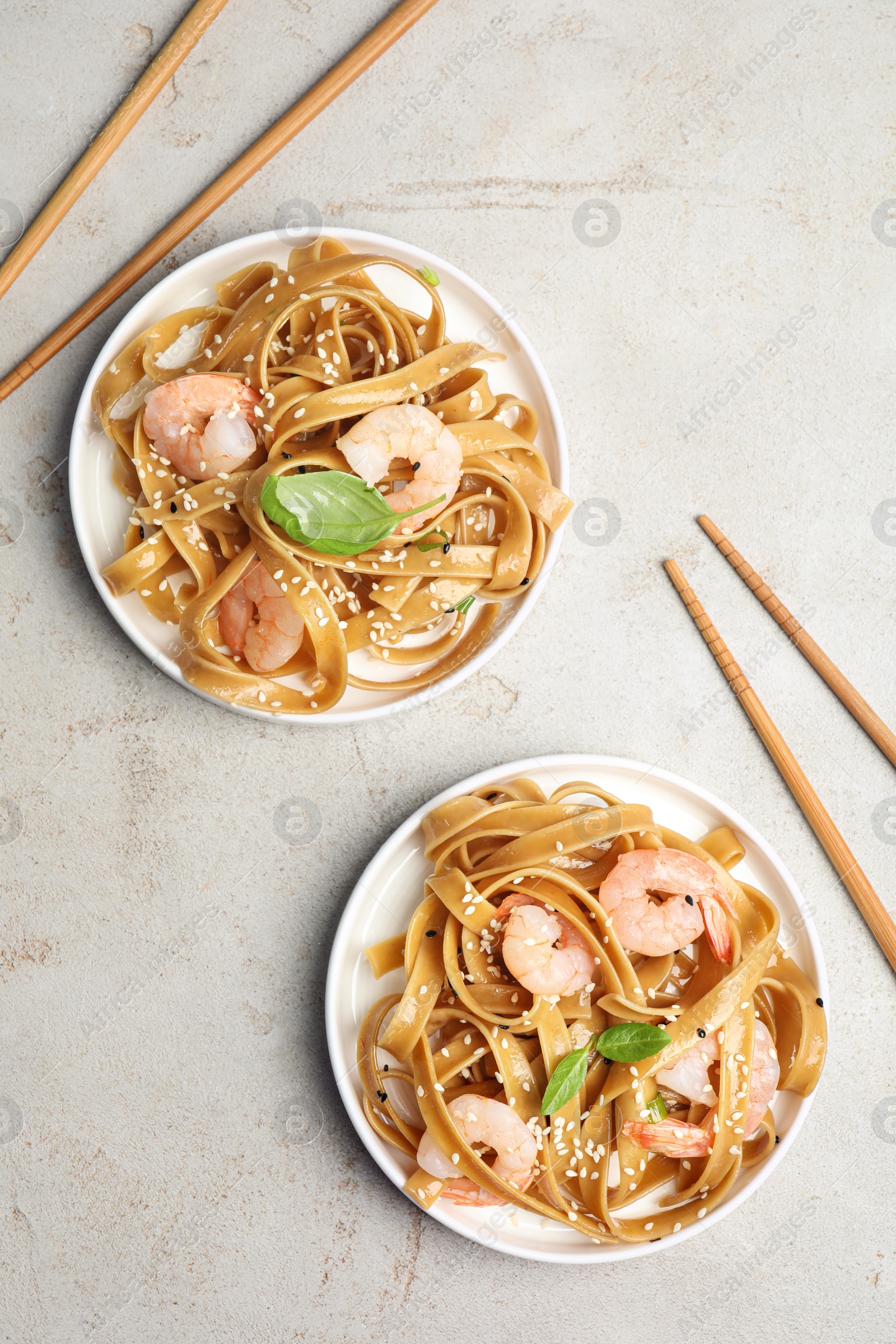 Photo of Tasty buckwheat noodles with shrimps served on light table, flat lay