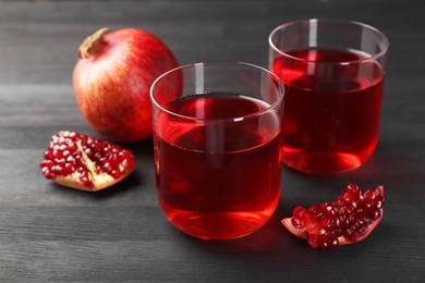 Photo of Tasty pomegranate juice in glasses and fresh fruits on black wooden table