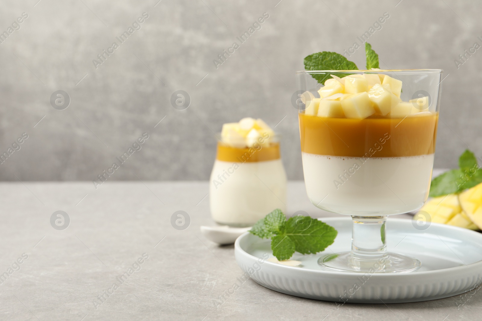 Photo of Delicious panna cotta with mango on grey table. Space for text