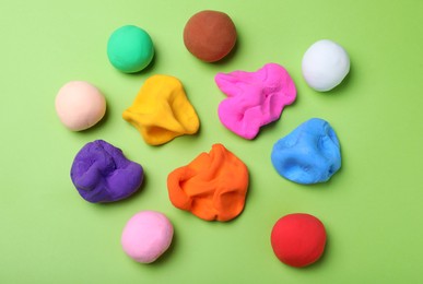 Photo of Colorful plasticine on green background, flat lay