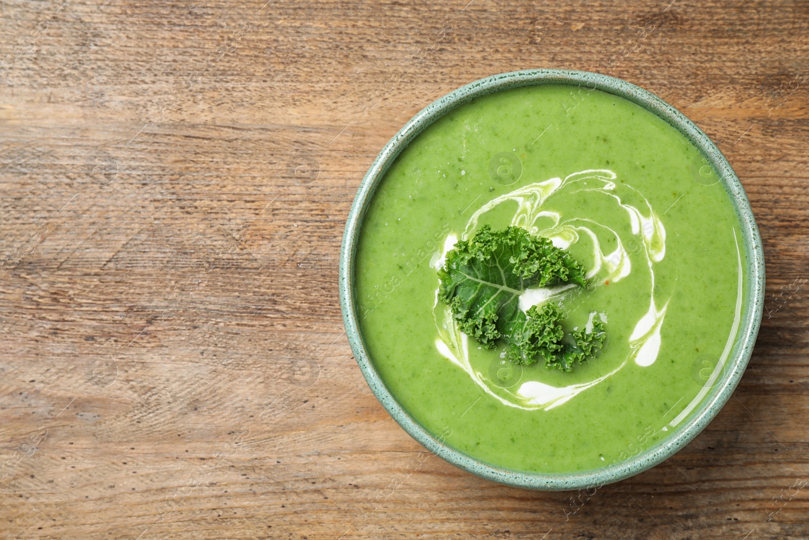 Photo of Tasty kale soup on wooden table, top view. Space for text