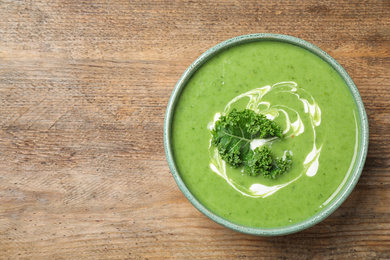 Photo of Tasty kale soup on wooden table, top view. Space for text