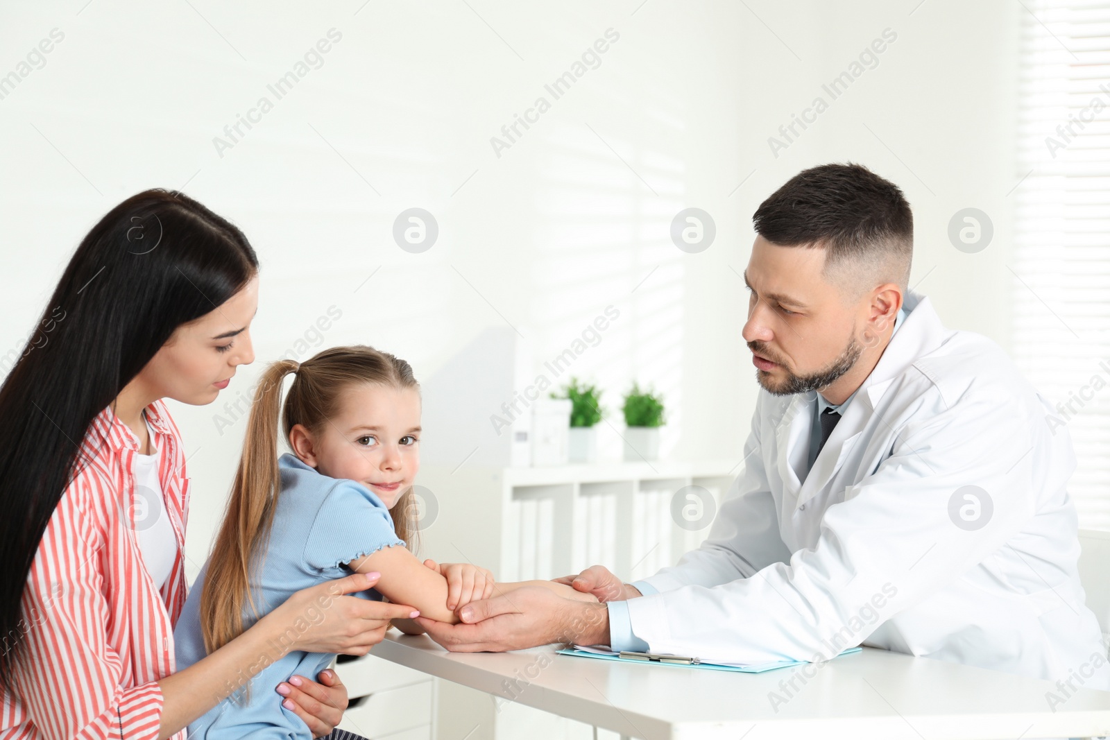 Photo of Little girl with mother visiting orthopedist at clinic