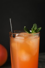 Photo of Tasty grapefruit drink with ice and mint in glass on black background, closeup