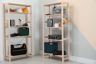 Photo of Wooden shelving units with different instruments near color wall. Stylish room interior