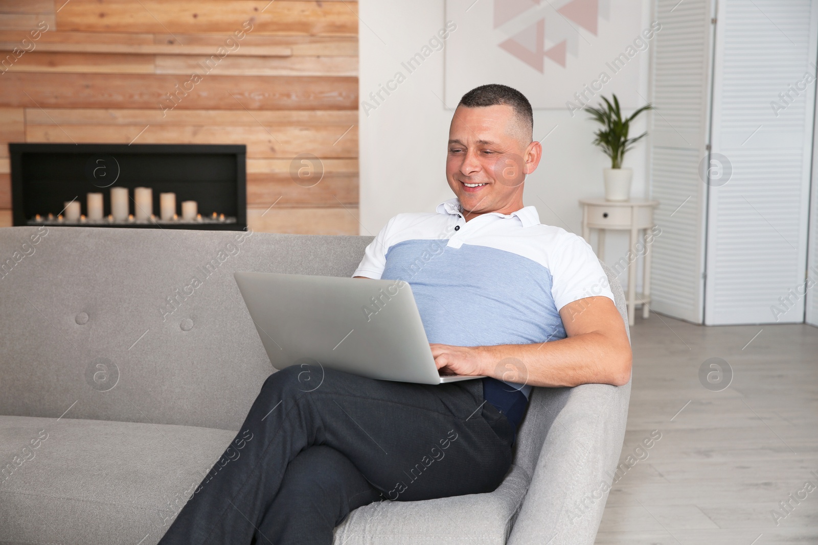 Photo of Mature man with laptop sitting on sofa at home