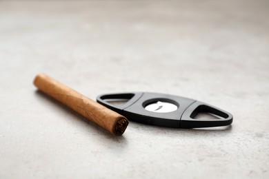 Photo of Cigar and guillotine cutter on light grey table