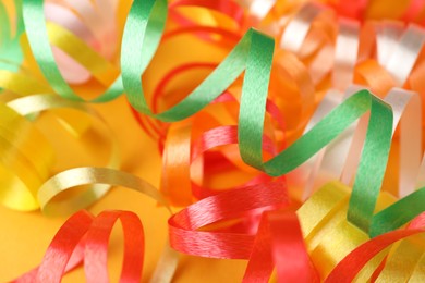 Photo of Colorful serpentine streamers on yellow background, closeup